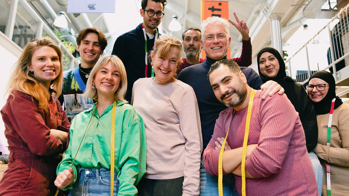 A group of colleagues of different ages and ethnicities in a atelier posing together for a photograph