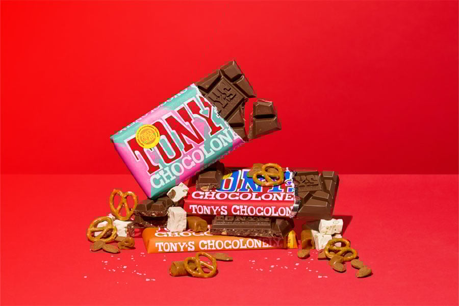 Tony’s Chocolonely bars, opened and stacked with pretzels, nuts, toffee, nougat, and chocolate