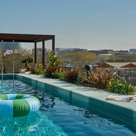Una piscina sul tetto di The Social Hub Barcellona con un salvagente che galleggia al suo interno e una splendida veduta sulla città