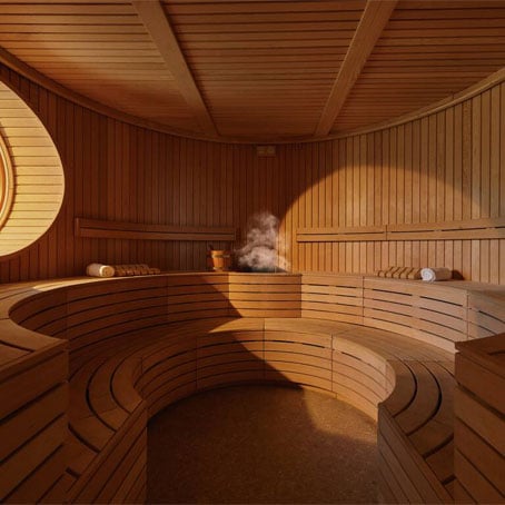 Una sauna vuota da cui sale il vapore e in cui filtra la luce