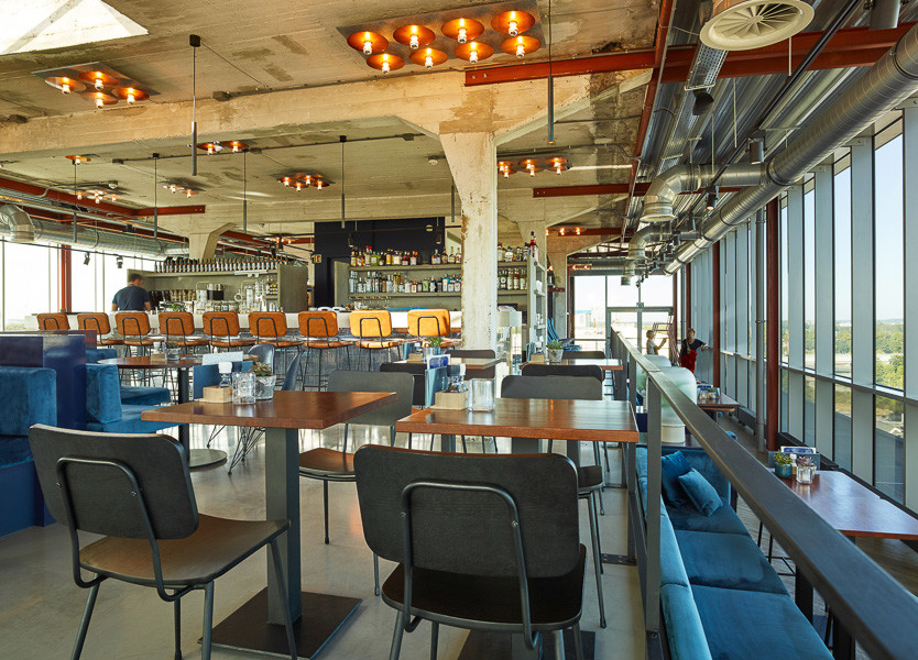 Rooftop bar at TSH Maastricht with black high bar tables, blue booth seating and sweeping city views