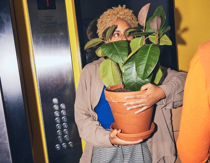 Girl holding a plant in the elevator at The Social Hub